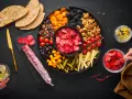 Planche apéro généreuse : charcuterie, fruits secs, olives, tomates, fromage, cornichons et pain. Une belle idée pour un moment convivial.