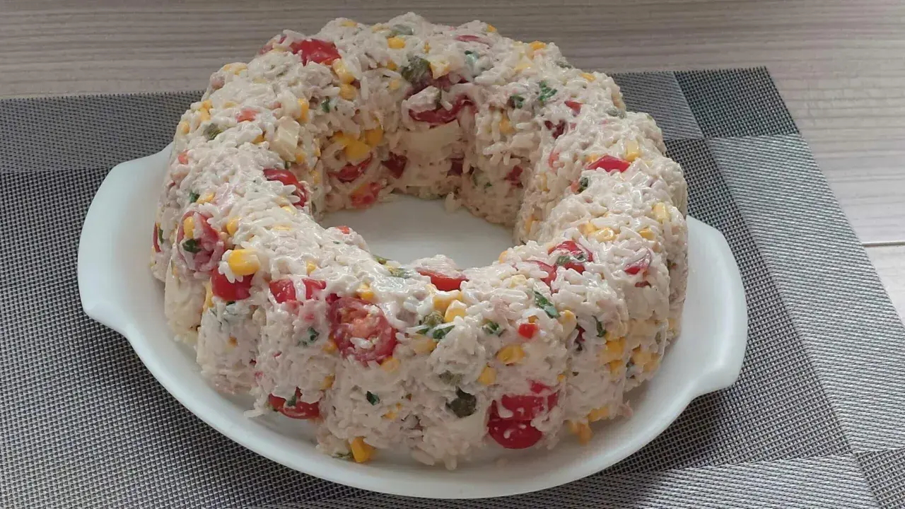 Une savoureuse salade de riz en forme de couronne, garnie de tomates cerises, de maïs et d'herbes fraîches. Un délice pour les yeux et les papilles !