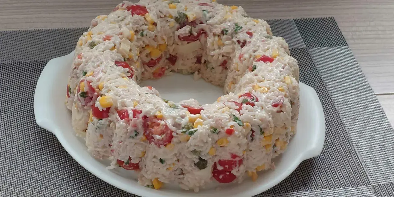 Une savoureuse salade de riz en forme de couronne, garnie de tomates cerises, de maïs et d'herbes fraîches. Un délice pour les yeux et les papilles !