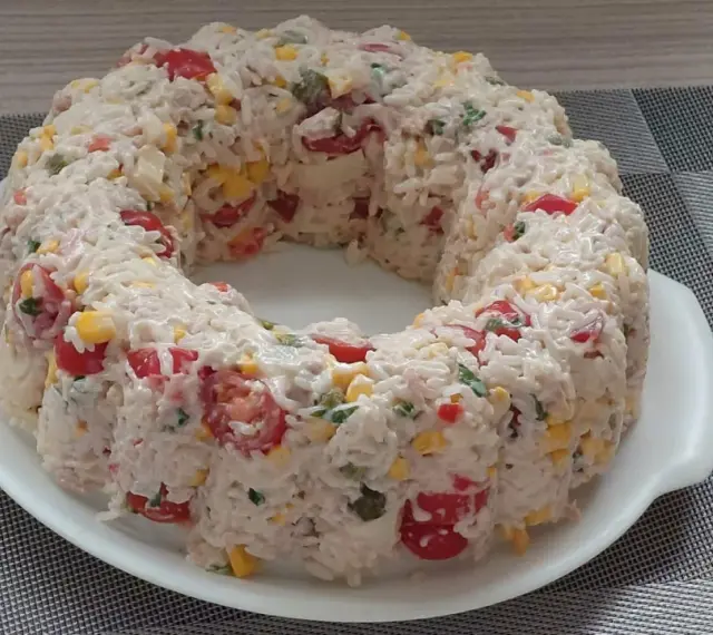 Une savoureuse salade de riz en forme de couronne, garnie de tomates cerises, de maïs et d'herbes fraîches. Un délice pour les yeux et les papilles !