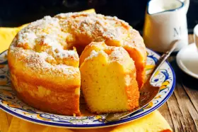 Gâteau sans gluten, saupoudré de sucre glace, sur une assiette décorée. Une part est coupée, prête à être dégustée.