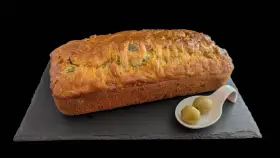 Un délicieux cake jambon olive, doré et moelleux, servi avec deux olives vertes sur une cuillère.