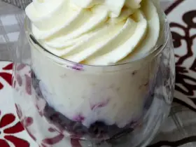Délicieuse mousse chocolat blanc aérienne, parsemée de fruits rouges, servie dans un verre.