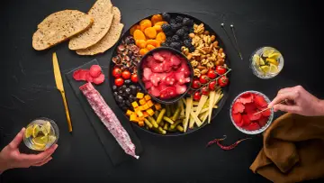 Planche apéro généreuse : charcuterie, fruits secs, olives, tomates, fromage, cornichons et pain. Une belle idée pour un moment convivial.