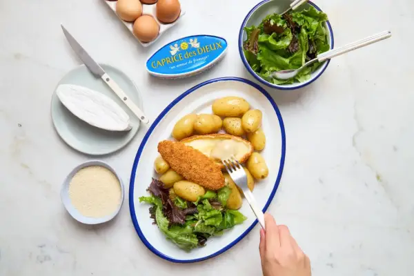 Délicieuse recette Caprice des Dieux pané, servi avec des pommes de terre et une salade verte. Le fromage coulant est irrésistible !