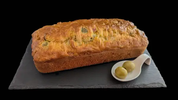 Un délicieux cake jambon olive, doré et moelleux, servi avec deux olives vertes sur une cuillère.
