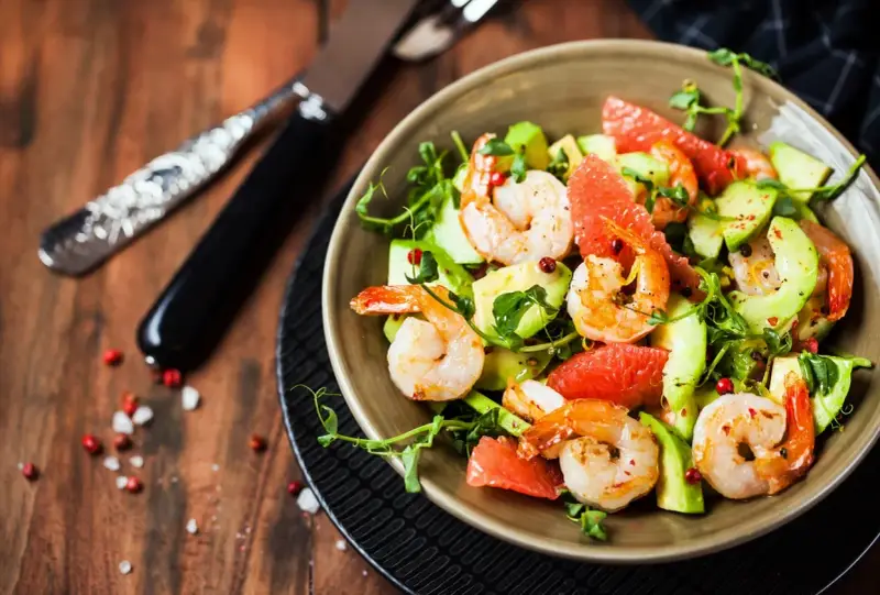 Salade avocat crevette fraîche et colorée, garnie de pamplemousse et de pousses vertes. Un délice léger.