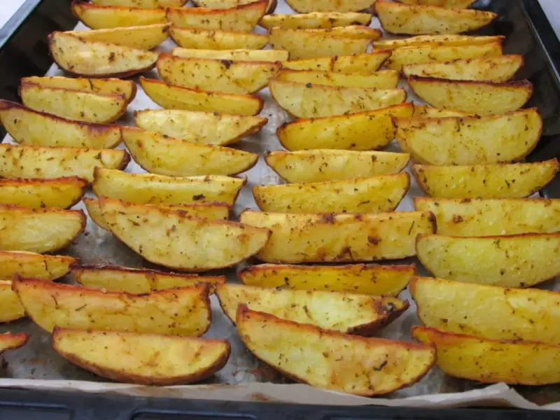 Des pommes de terre rôties au four croustillantes, dorées et assaisonnées, disposées sur une plaque de cuisson.