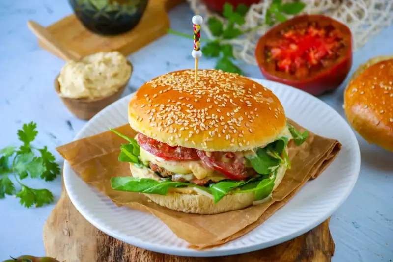 Un délicieux pain burger maison garni de légumes frais, de fromage fondant et d'une viande savoureuse. Un régal pour les yeux et les papilles !
